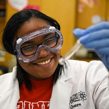 PLTW student in labcoat with safety glasses